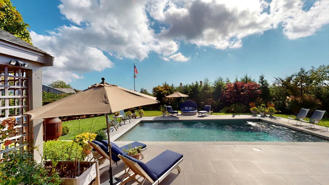 The heated pool at Stowaways, ringed by bluestone and loungers beneath the shingled house.